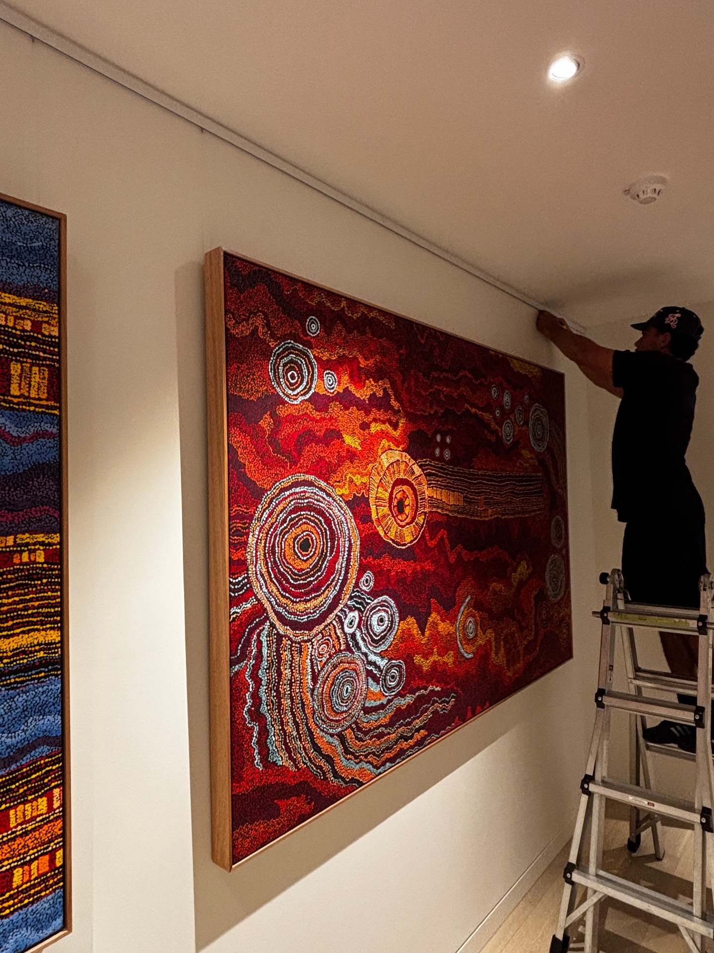 Installer hanging large indigenous artwork